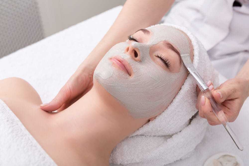 Facial mask being applied to relaxed woman at spa.